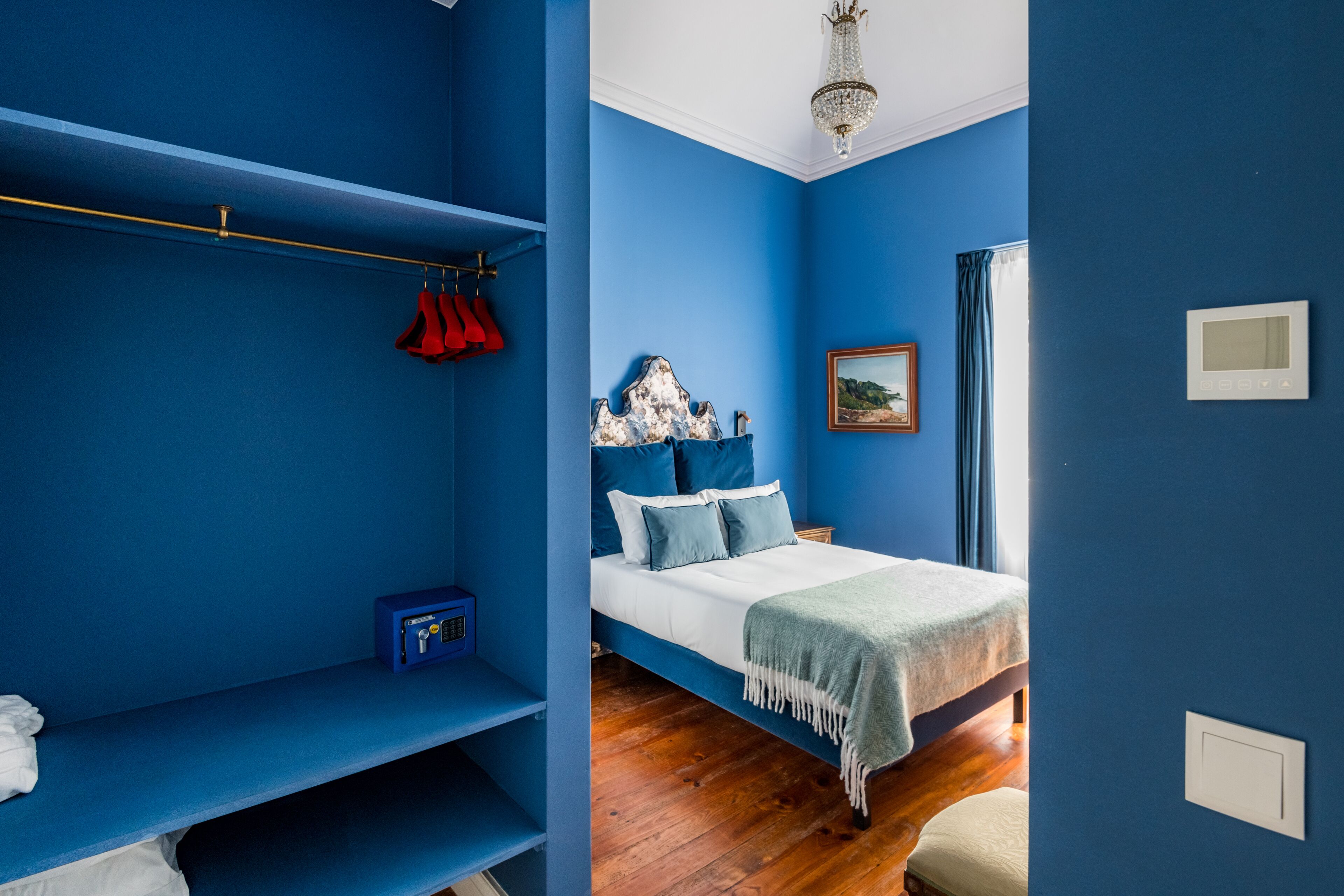 A bedroom with a bed, a wardrobe, a bedside table, and a window with curtains.