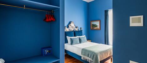 A bedroom with a bed, a wardrobe, a bedside table, and a window with curtains.