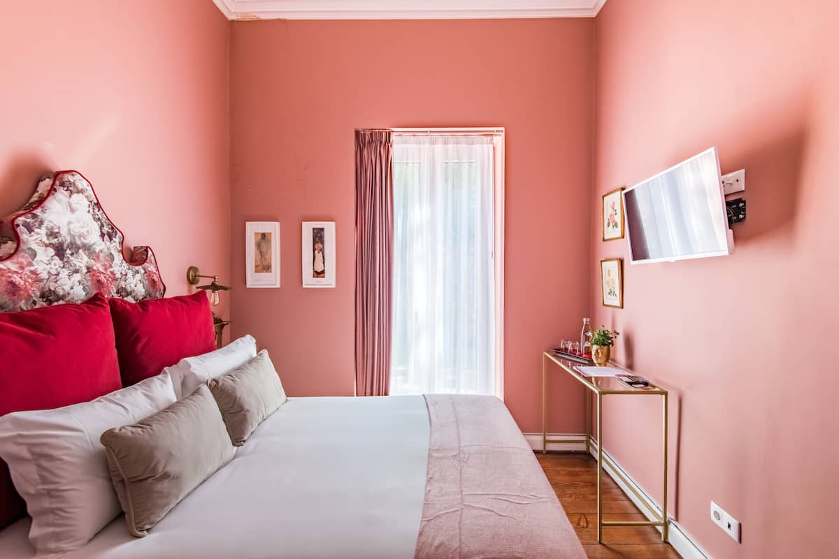 Ein Schlafzimmer mit Bett, Schreibtisch und einem fenster mit Vorhängen.