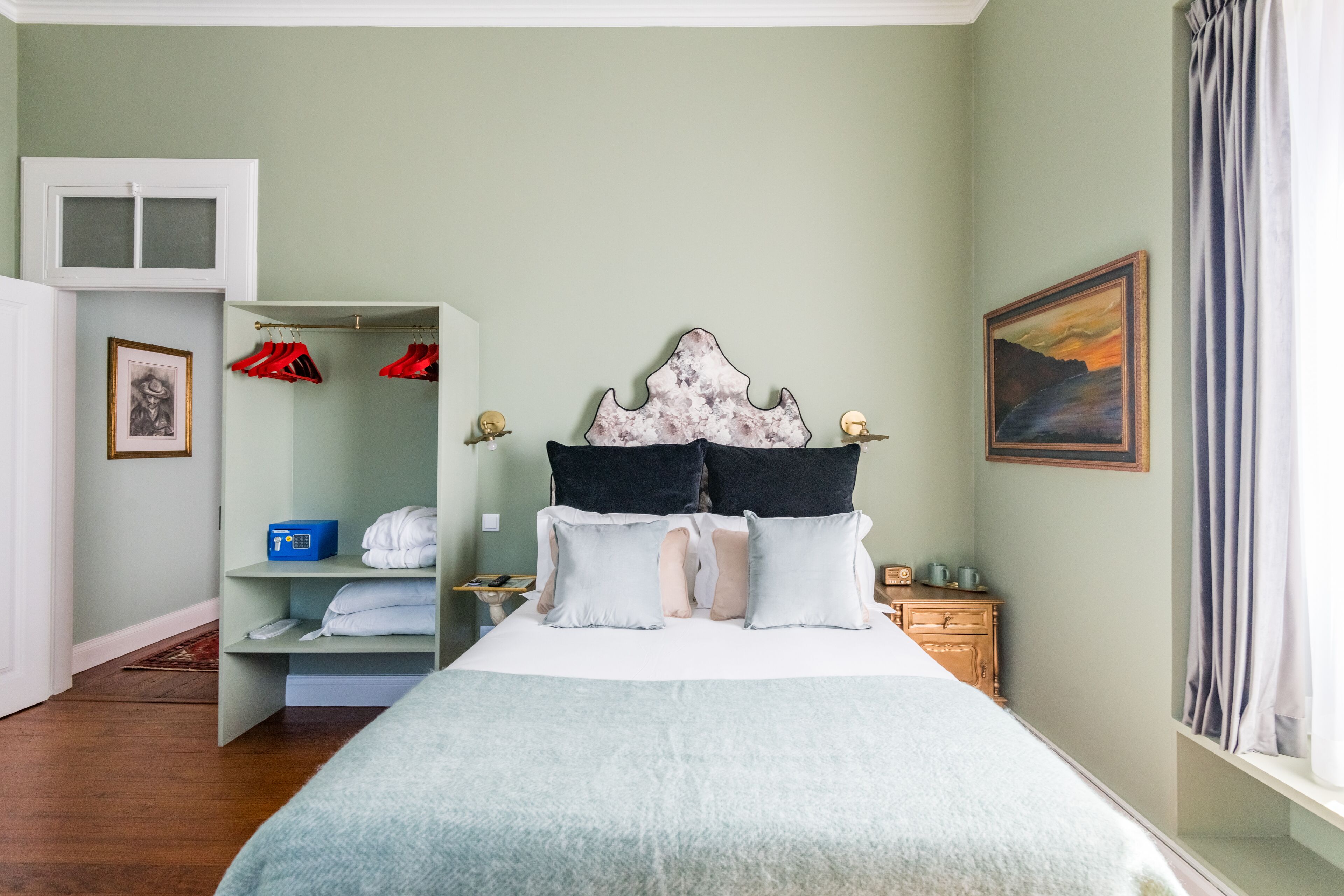 Une chambre à coucher avec un lit, une armoire, une table de chevet et un tableau accroché au mur.