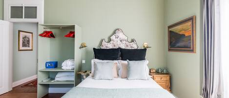Une chambre à coucher avec un lit, une armoire, une table de chevet et un tableau accroché au mur.