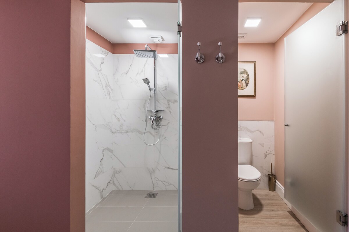 Une salle de bain avec douche, toilettes et murs en marbre.