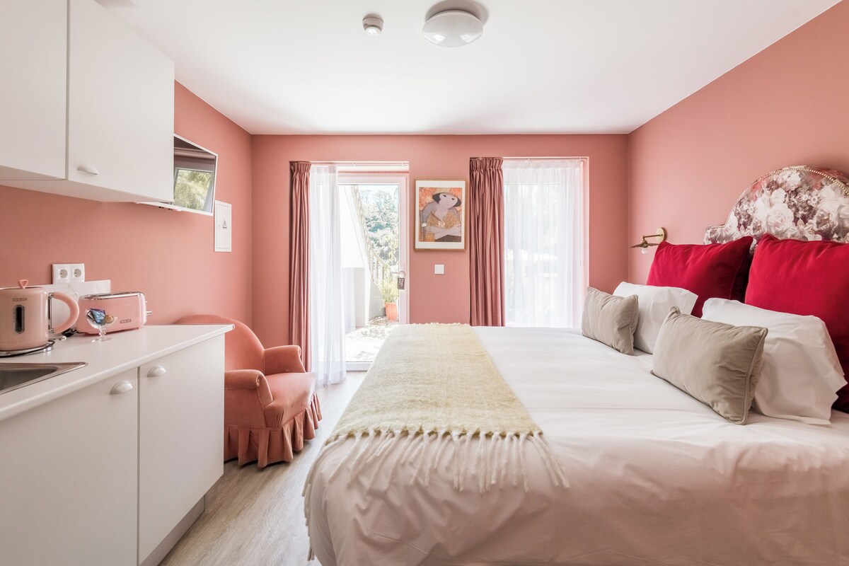 Un dormitorio con cama, escritorio, silla y ventana.