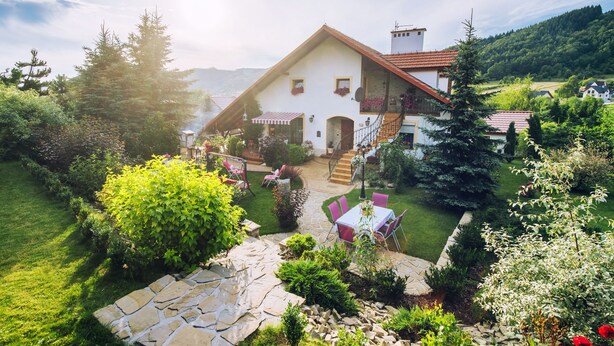 A traditional chalet with a stone patio, outdoor seating, and a lush garden. - Villa Agnes (Myslenice)