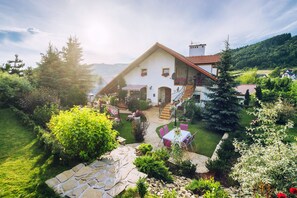 A traditional chalet with a stone patio, outdoor seating, and a lush garden.