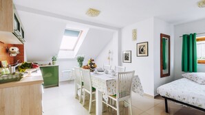 A modern, well-lit room with a dining area, a bed, and a kitchen. - Villa Agnes (Myslenice)