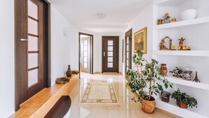 A hallway with a wooden bench, a rug, and potted plants. - Villa Agnes (Myslenice)