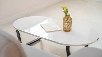 Una mesa blanca con un libro y un florero de mimbre con flores.
