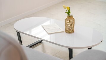 A white table with a book and a wicker vase with flowers.