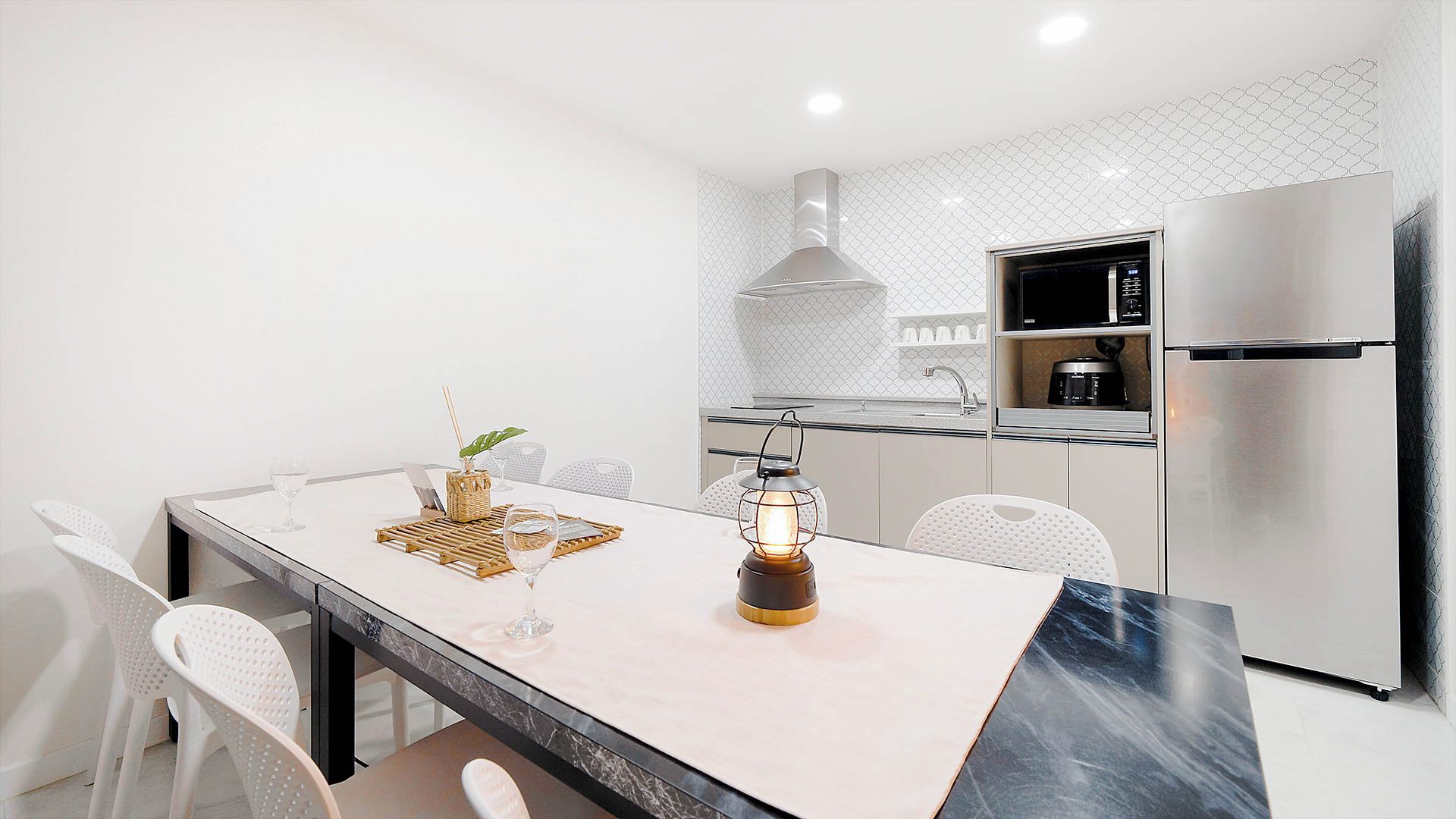 Una cocina moderna con encimera de mármol, electrodomésticos de acero inoxidable y una lámpara colgante.