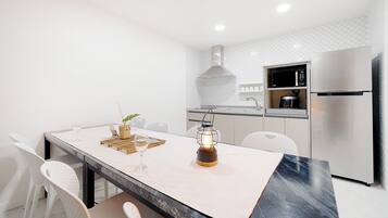 Una cocina moderna con encimera de mármol, electrodomésticos de acero inoxidable y una lámpara colgante.