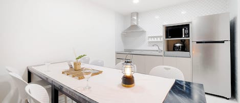 Een moderne keuken met een marmeren aanrecht, roestvrijstalen apparatuur en een hanglamp.