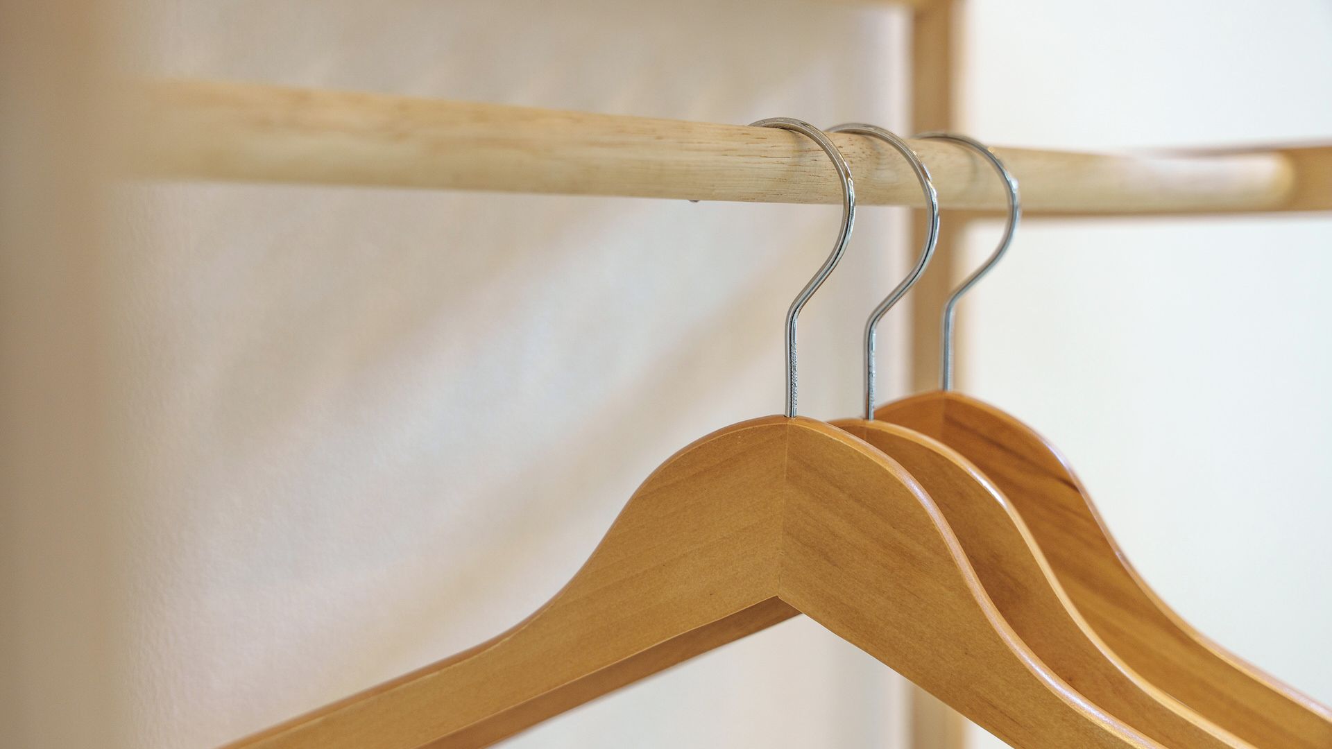 A wooden hanger rod with a metal hook and a wooden hanger.