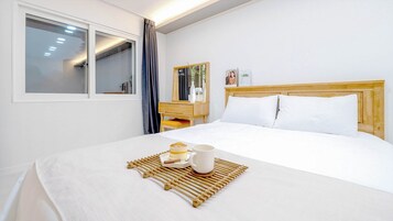 Habitación de hotel con cama, mesita de noche y ventana con cortinas.