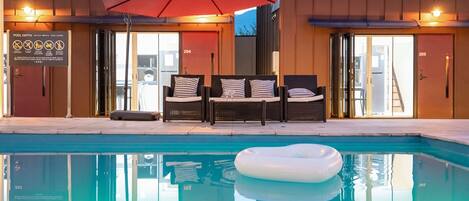 A pool area with lounge chairs and an umbrella, a sign indicating pool depth, and doors numbered 204 and 205.