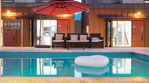 Un espace piscine avec des chaises longues et un parasol, un panneau indiquant la profondeur de la piscine, et des portes numérotées 204 et 205.