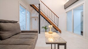 Un salon moderne avec un canapé, une table avec une lampe et un escalier.