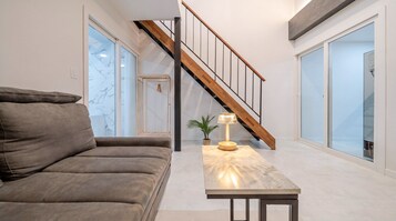 Una sala moderna con un sofá, una mesa con una lámpara y una escalera.