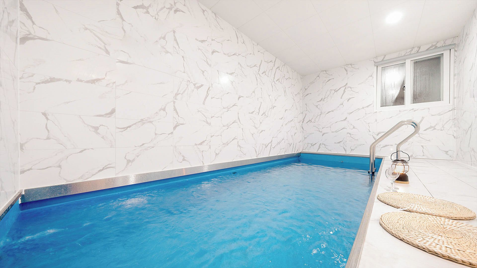 Una piscina con paredes de mármol blanco y un borde azul.