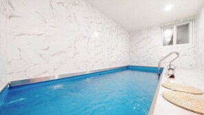 Ein Schwimmbecken mit weißen Marmorwänden und einem blauen Beckenrand.