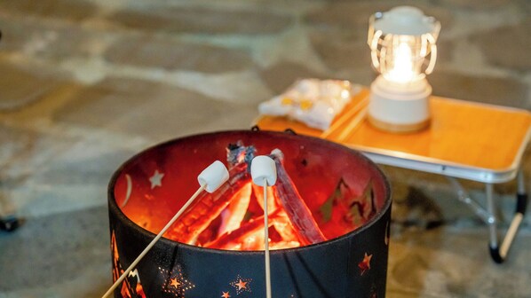 Un feu de camp avec des guimauves, une lanterne et une table pliante.