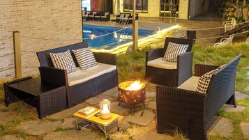 Un área de estar exterior con mobiliario de mimbre y una chimenea.