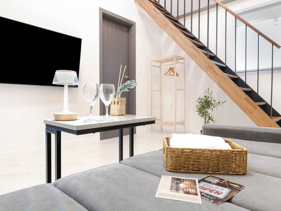 Una sala de estar moderna con un sofá gris, una mesita con una lámpara y una cesta de mimbre.