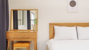 Une chambre avec un lit en bois, des oreillers blancs, une table de chevet en bois, un miroir et une affiche encadrée représentant un signe du zodiaque accrochée au mur.