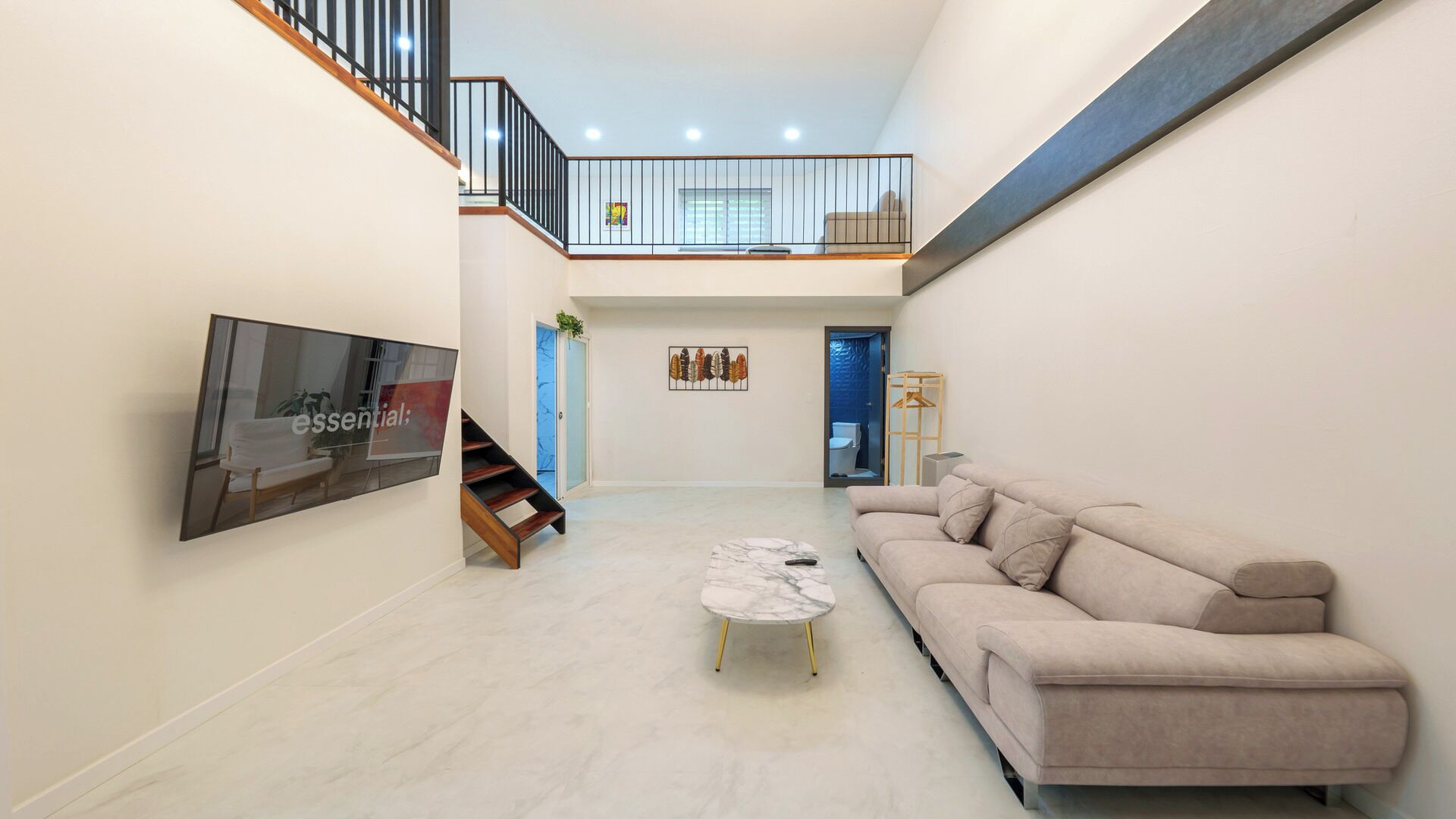 A spacious living area with a sofa, a coffee table, and a staircase leading to an upper level.