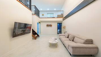 A spacious living area with a sofa, a coffee table, and a staircase leading to an upper level.