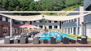 Ein Poolbereich mit Sitzgelegenheiten im Freien und Blick auf ein Gebäude im Hintergrund.