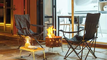 Un espace extérieur accueillant avec deux chaises, une petite table et un foyer.