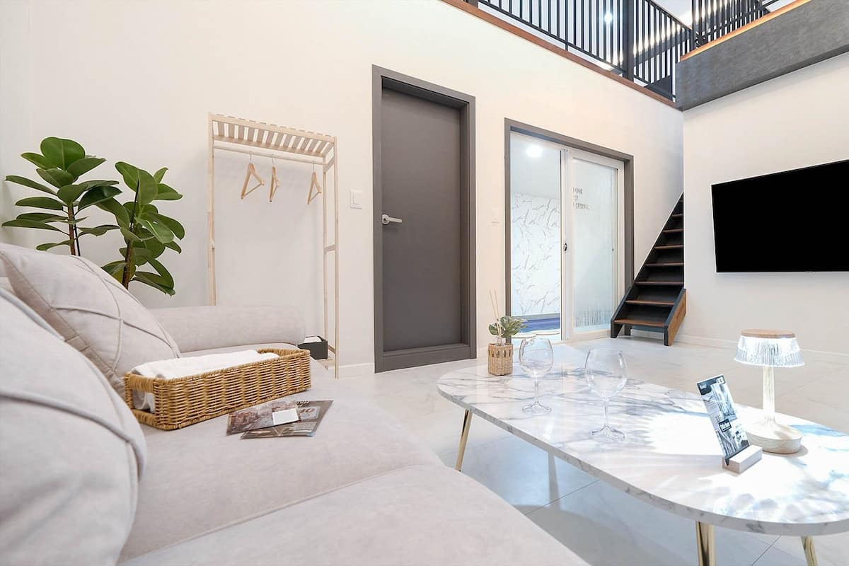 Un salon moderne avec un canapé, une table basse, un téléviseur fixé au mur et un escalier menant à un niveau supérieur.