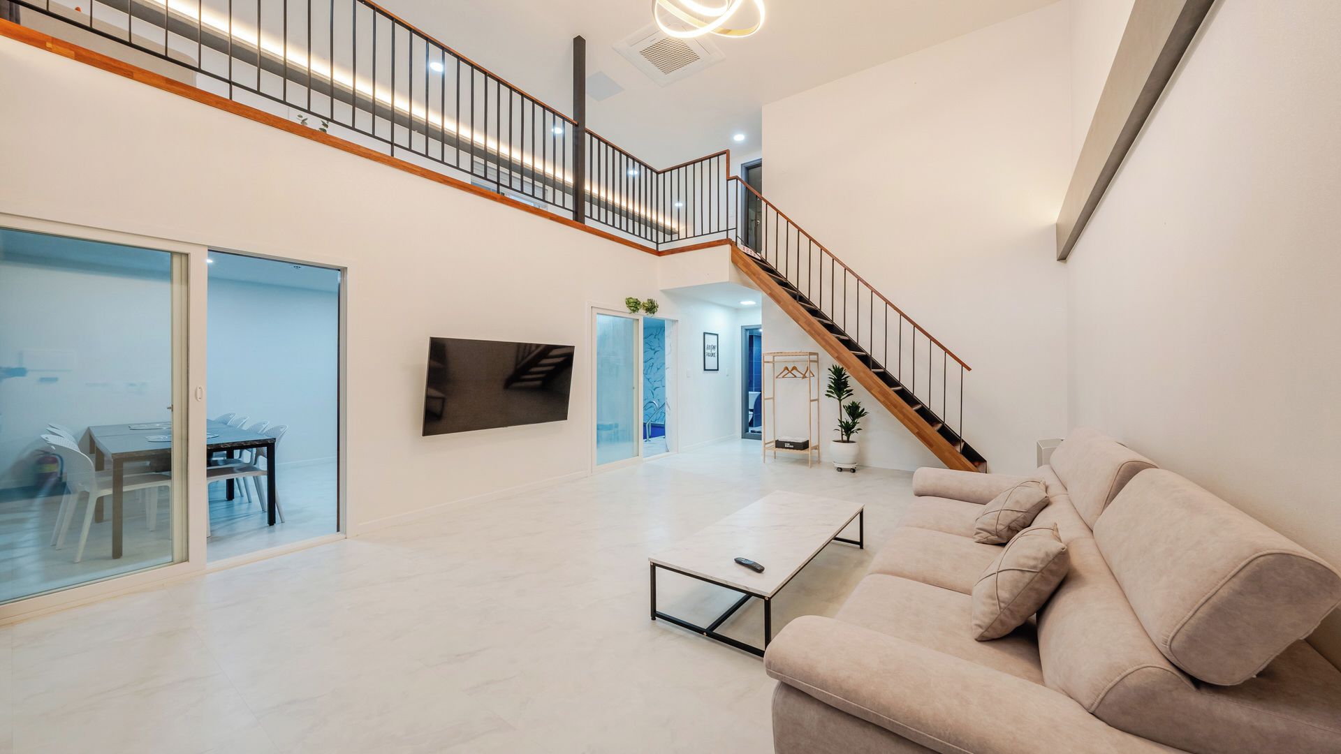 A spacious living area with a sofa, a coffee table, and a staircase leading to an upper floor.