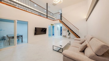 Amplia sala de estar con sofá, mesa de centro y una escalera que conduce a un piso superior.