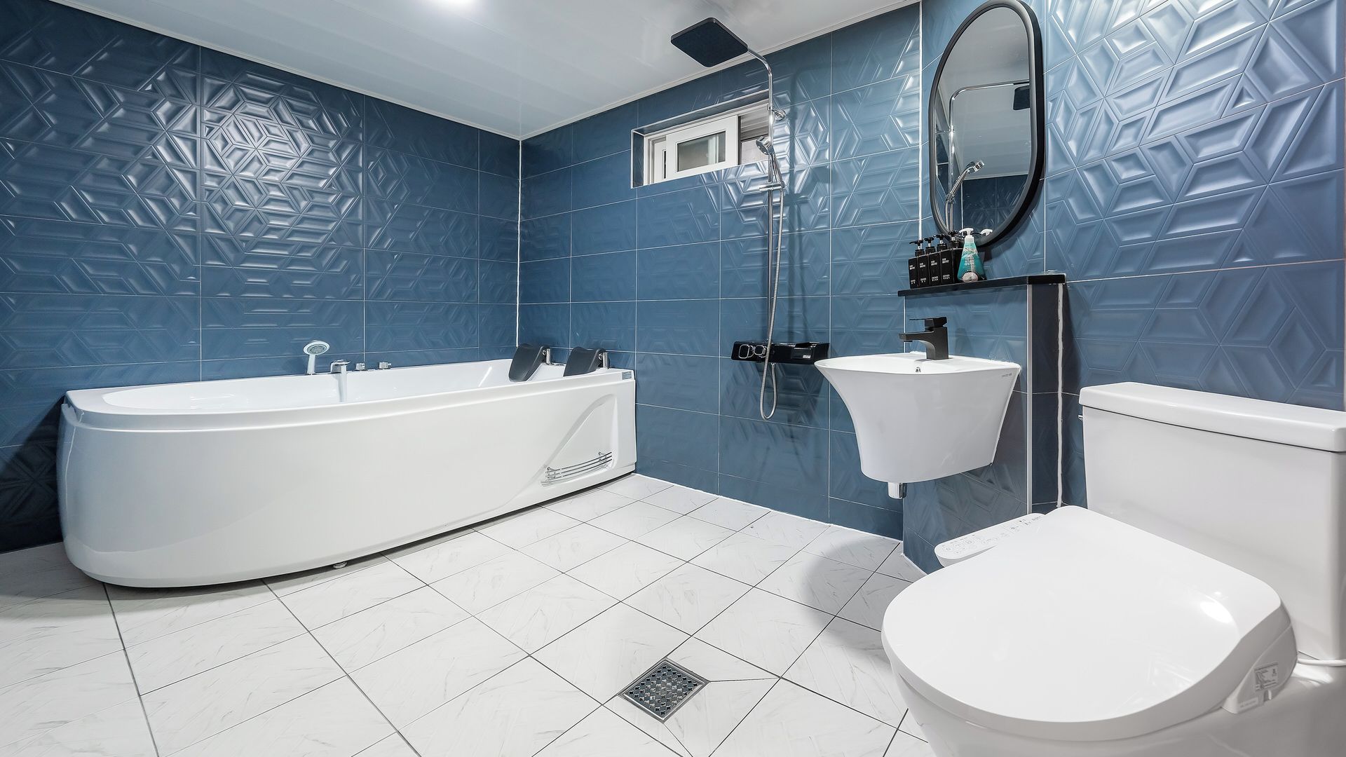 A modern bathroom with a freestanding bathtub, a wall-mounted sink, and a toilet.