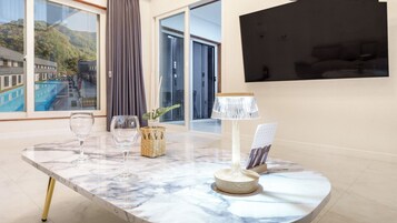 Et marmorbord med to glas, en flettet kurv og en lampe i et moderne rum med store vinduer og udsigt til en bygning.