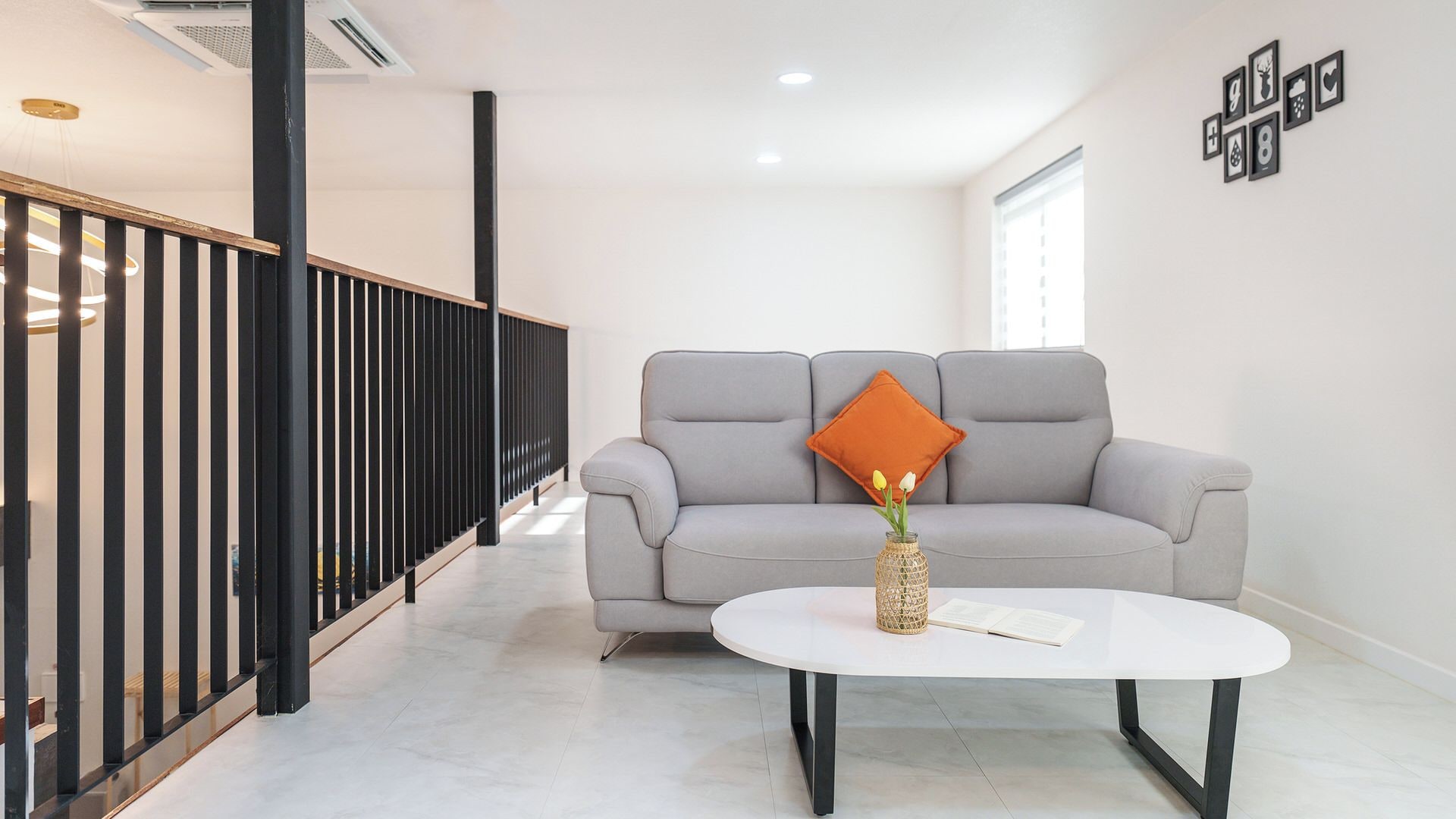 A modern living room with a grey sofa, a white coffee table, and a decorative vase with flowers.
