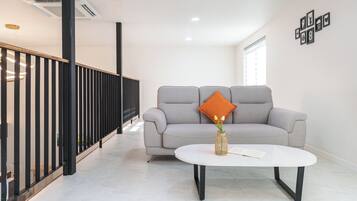 Ein modernes Wohnzimmer mit einem grauen Sofa, einem weißen Couchtisch und einer dekorativen Vase mit Blumen.