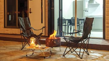 An outdoor seating area with two chairs and a small table, a portable heater, and a fire pit.