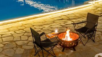 A stone patio with a fire pit and two chairs.