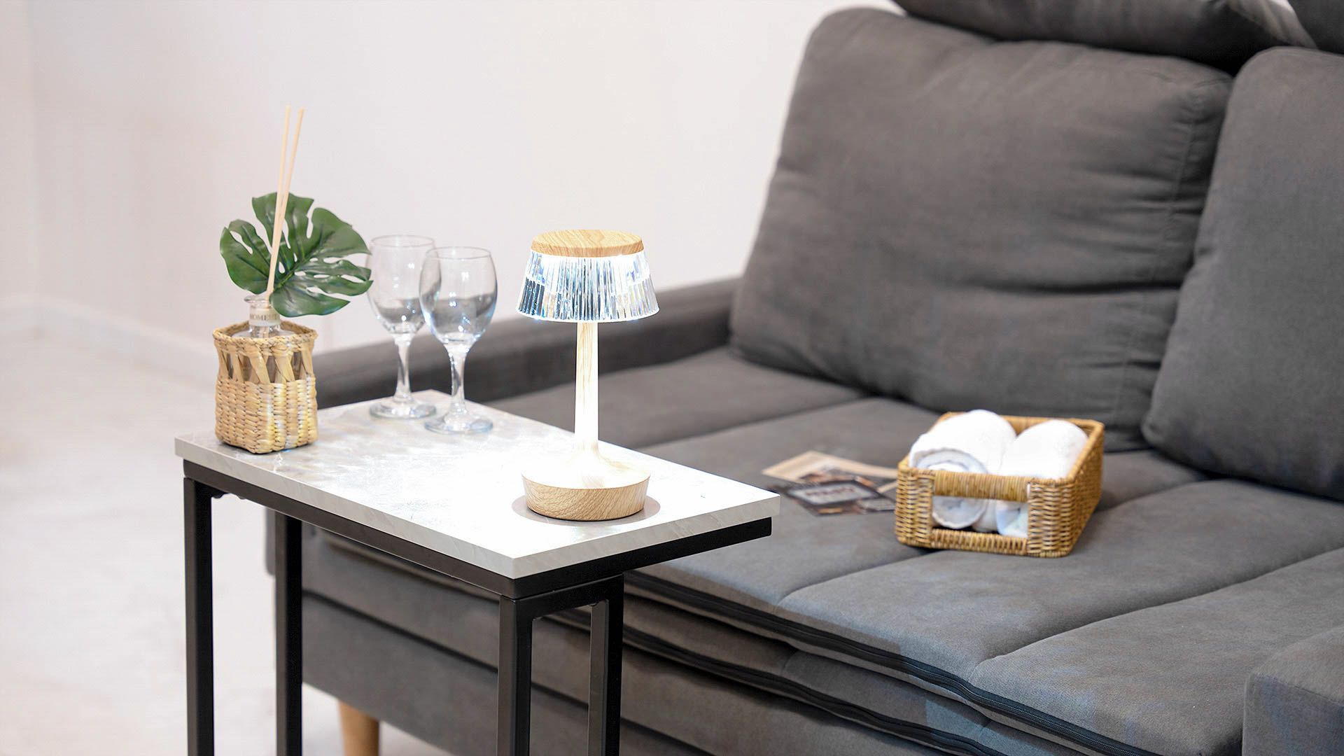 A small table with a lamp, glasses, and a plant.