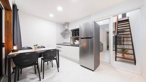 A modern kitchen with a stainless steel refrigerator, a microwave, and a toaster. There is a dining table with chairs and a small plant on the table. - Gapyeong Orion Poolvilla Pension (Gapyeong)
