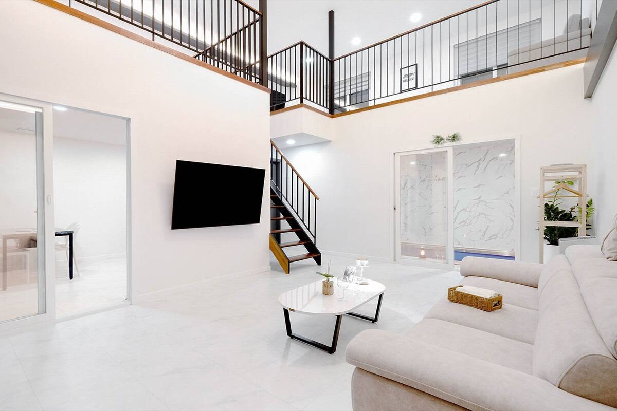 Un vaste espace de vie agrémenté d’un escalier moderne, d’un téléviseur à écran plat et d’un canapé confortable.