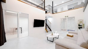 Un vaste espace de vie agrémenté d’un escalier moderne, d’un téléviseur à écran plat et d’un canapé confortable.