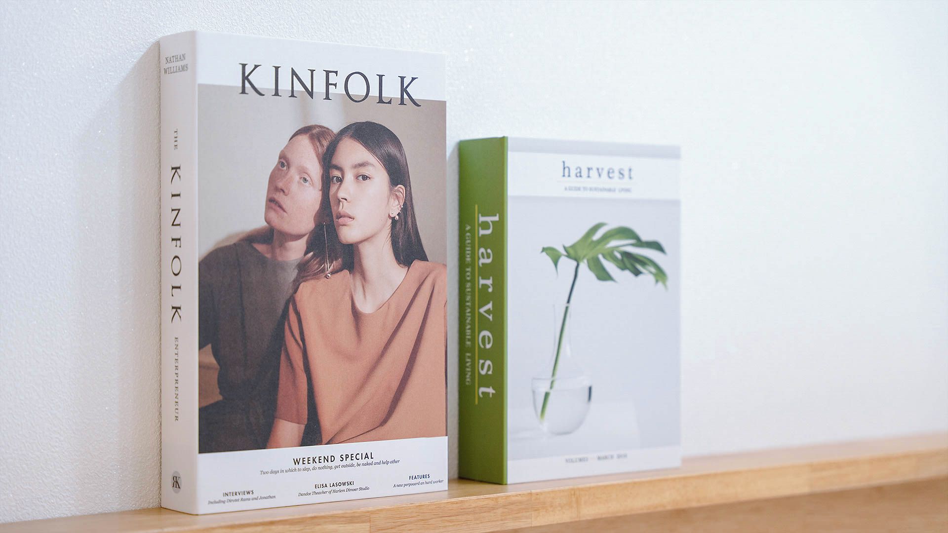 Two books titled 'KINFOLK' and 'harvest' on a shelf.