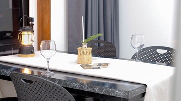 Una mesa con una vela, dos copas, una planta pequeña y un menú.