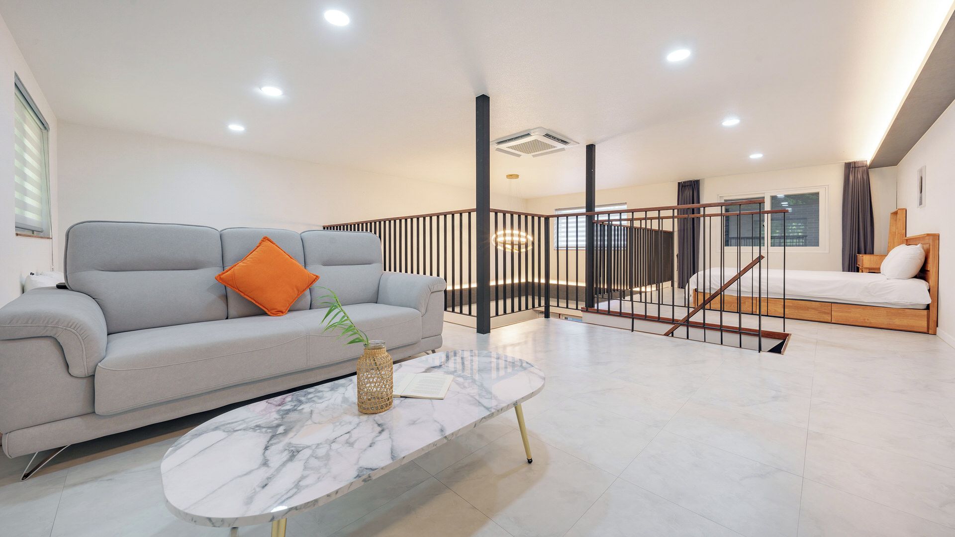 Ein modernes Wohnzimmer mit einer Couch, einem Couchtisch und einer Treppe, die zu einem Schlafzimmer führt.