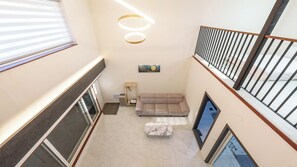 Ein mehrgeschossiges Interieur mit einer Couch und einem kleinen Tisch, einem Bild an der Wand und einer Treppe mit Geländer.
