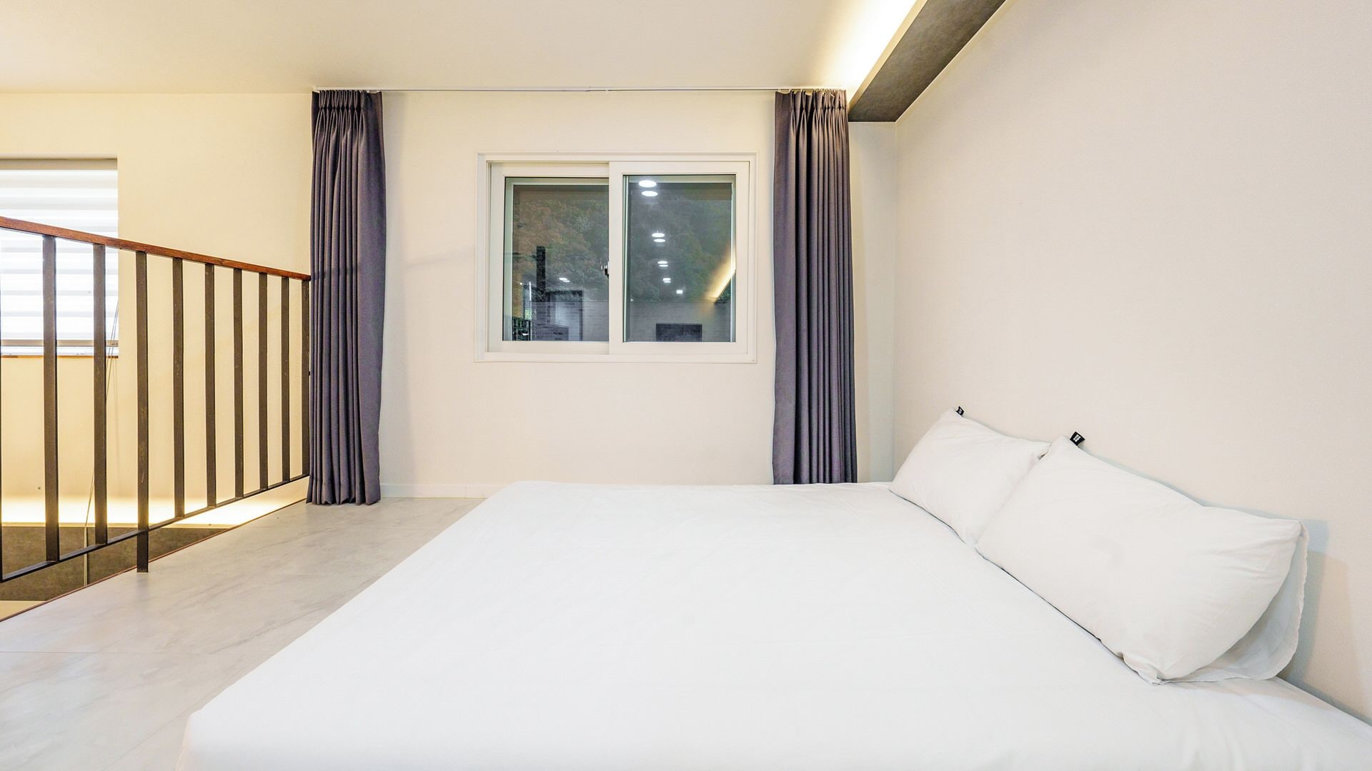 Ein Schlafzimmer mit einem Bett, einem Fenster und einer Treppe.